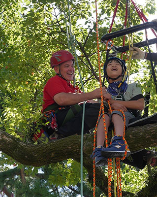 John Gathright and a young tree climber reach a treetop