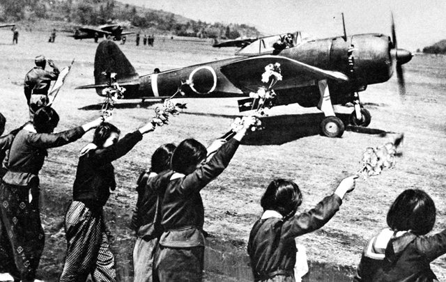 Chiran high school girls are waving farewell with cherry blossom branches to a taking-off kamikaze pilot.
