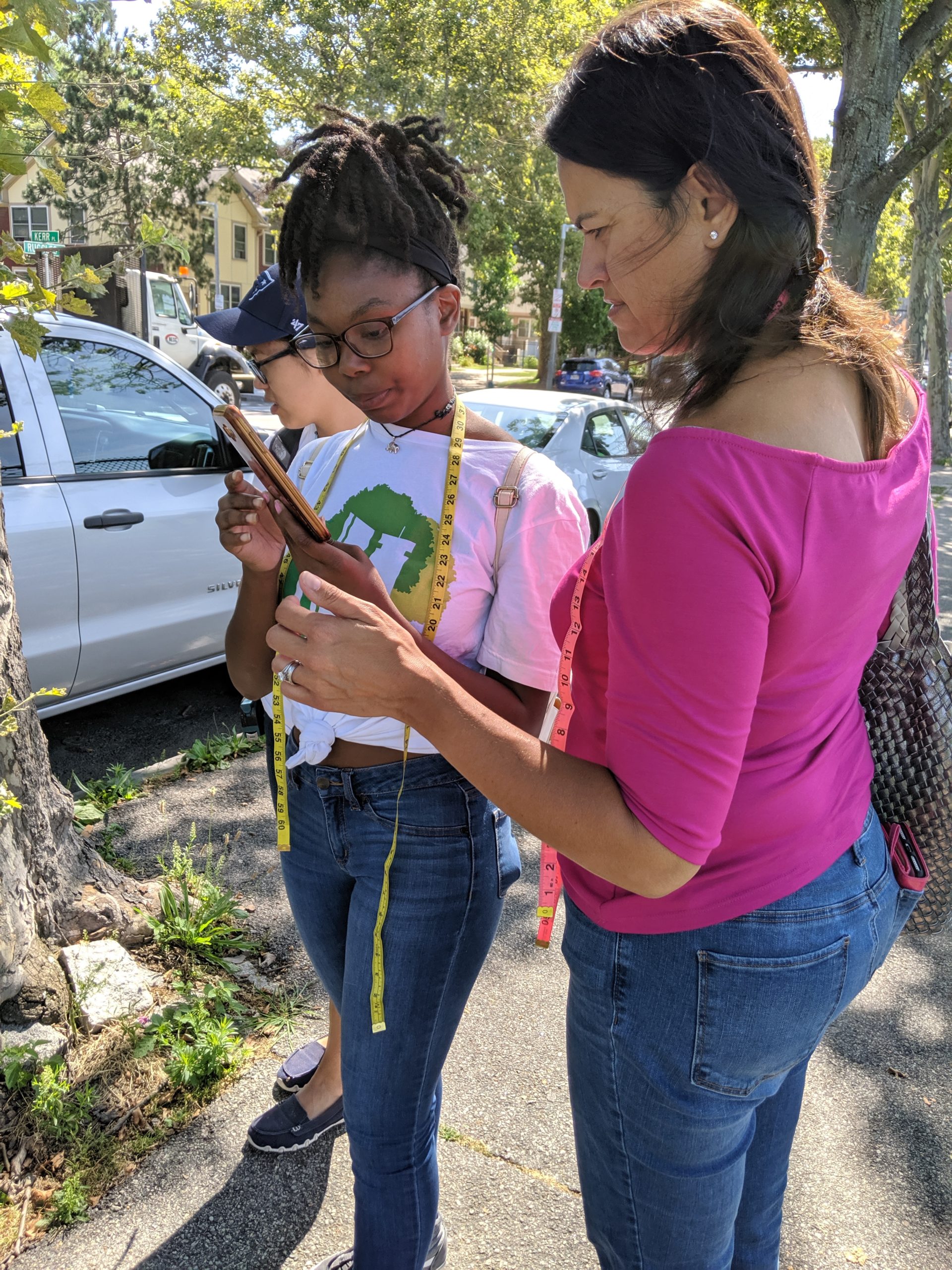 Teen Urban Tree Corps member Maya Hall (left) shows Boston City Councilor Anissa Essaibi George the process for recording tree inventory data.