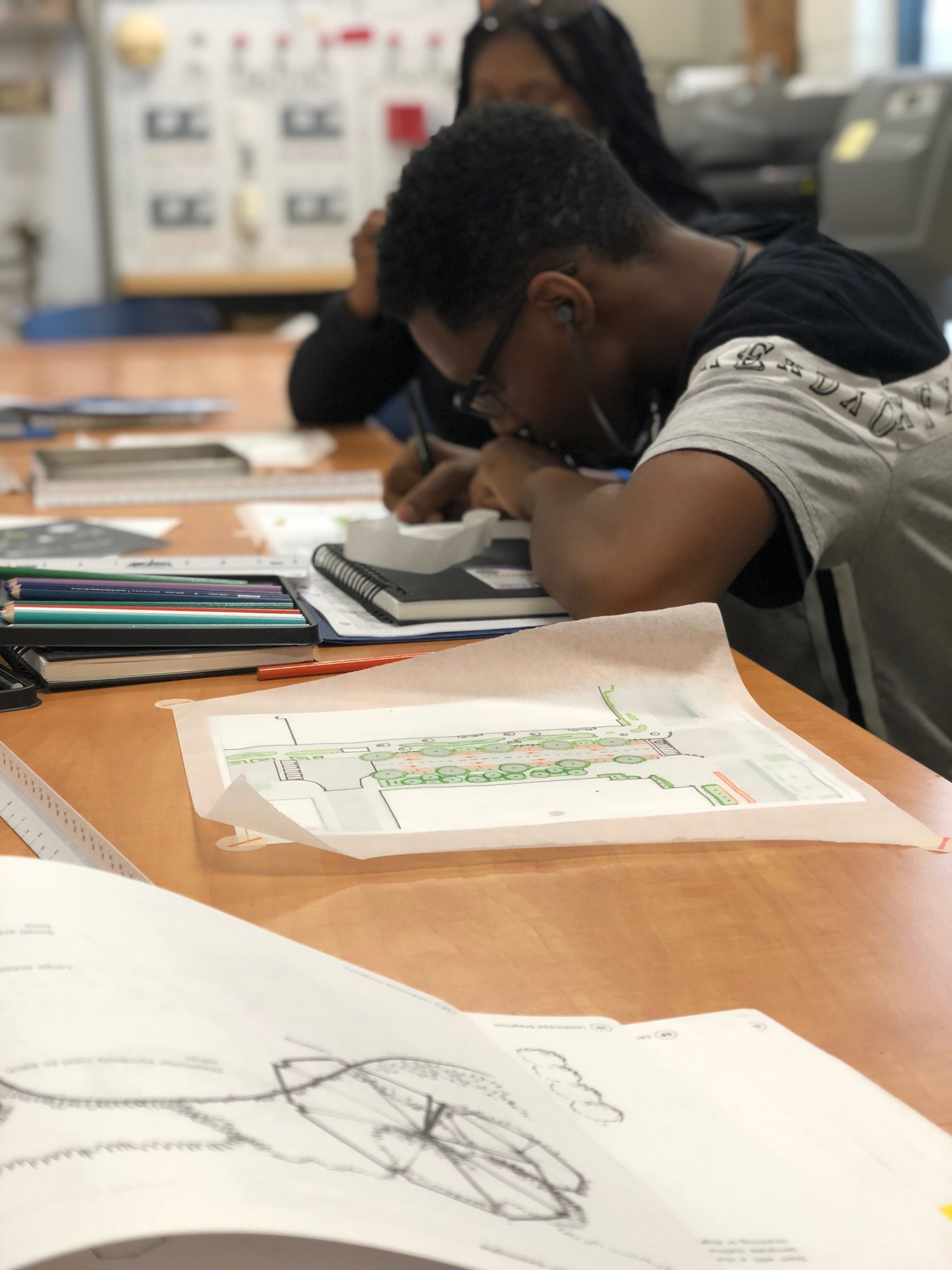 High school senior Quentin, a participant in The Studio DC, draws a plan of trees in bioretention in a Washington, D.C. landscape.