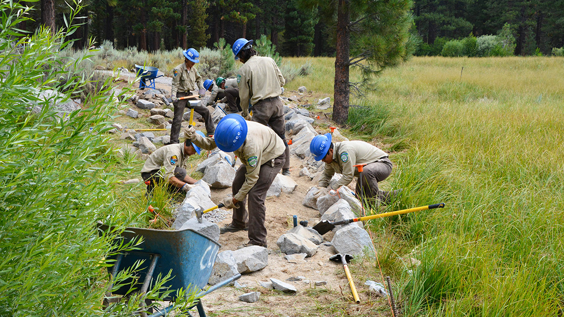 Tahoe Center California Conservation Corps members shape rocks to create the siding for an ADA accessible trail at Grover Hot Springs State Park in Markleeville, Calif.