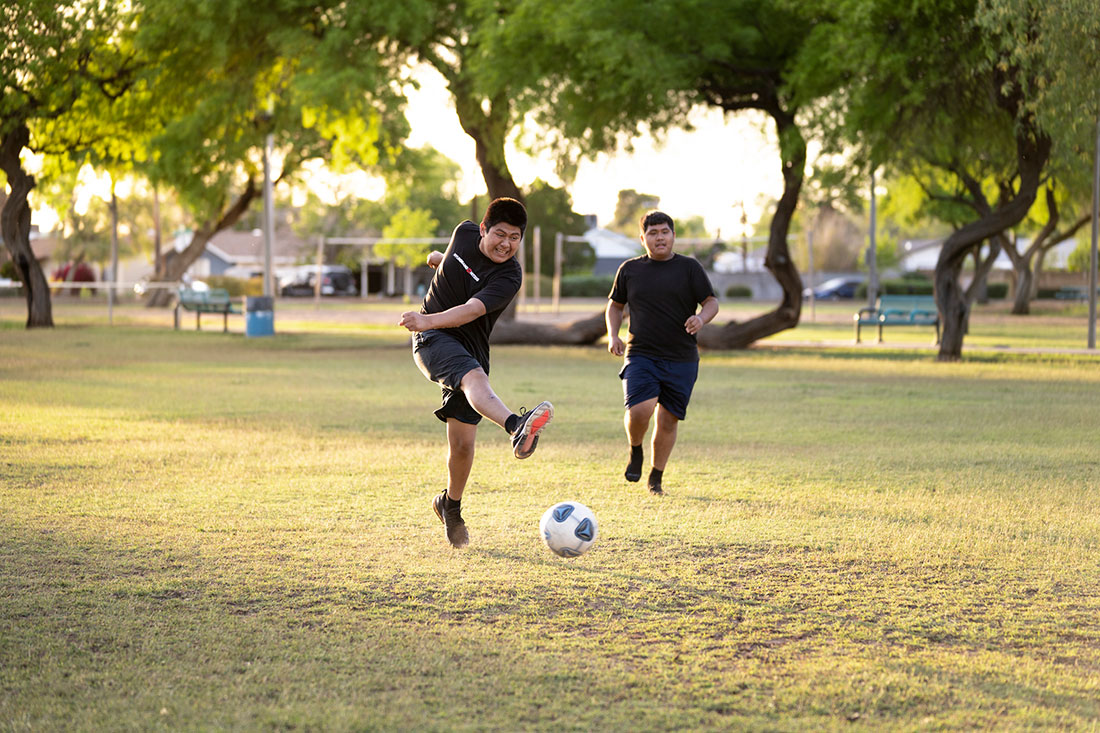 Two brothers spend quality time together playing soccer in the fields of Mitchell Park in Tempe, Ariz.