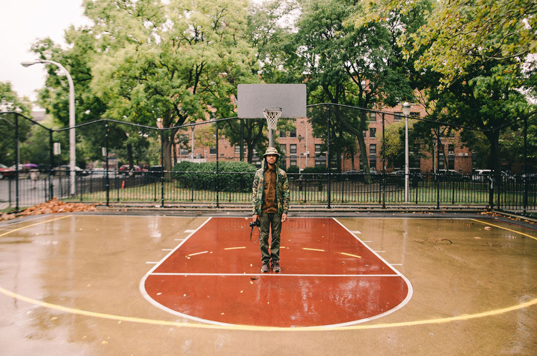 Visual Artist Steven John Irby stops to take a selfie on a Bed-Stuy basketball court on his way to his apartment in New York, N.Y. Behind him sits an affordable housing building adorned with some of the biggest trees on the street. When Irby is creating, he asks himself, “Which moments are worth stopping time for?”
