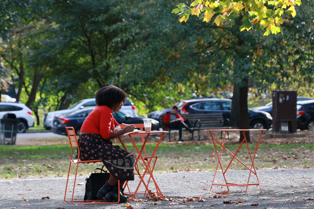 A woman finds a moment to journal beneath the trees in Philadelphia’s Clark Park.